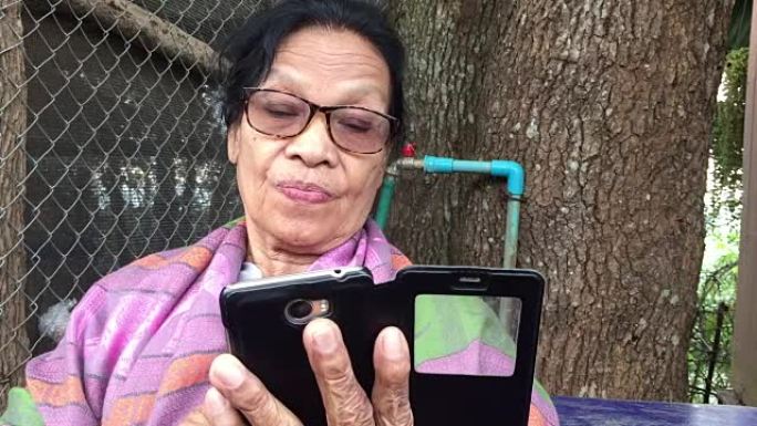 使用智能手机的快乐成熟老妇肖像