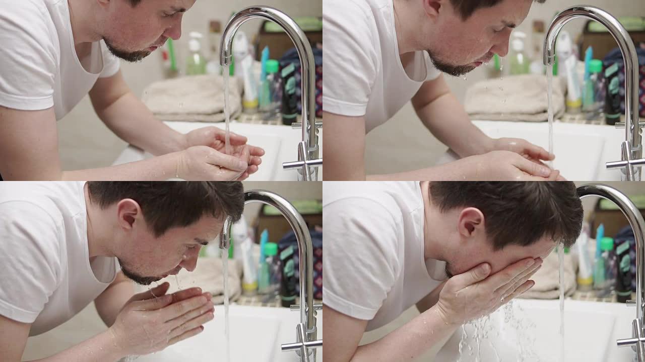 一个年轻而有胡子的男人在浴室的水龙头下洗脸