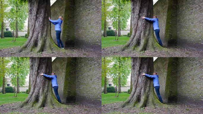 一个经历积极情绪的女人，拥抱树的巨大宽度。