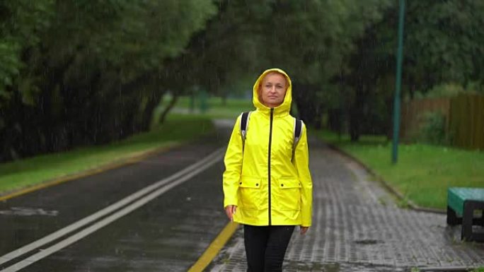 年轻美丽的幸福女人穿着黄色雨衣享受雨水。
