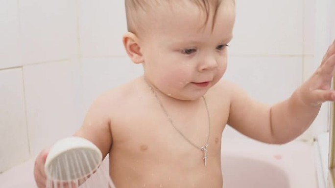 男婴浴室里有游戏水的淋浴。带十字架吊坠的婴儿