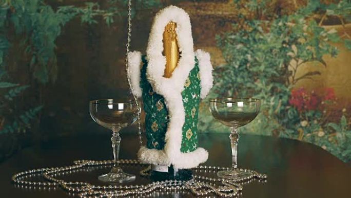一条银链缠绕着一瓶香槟和两杯。桌子上放着一瓶香槟和酒杯。灿烂的银珠上升。圣诞节和新年的概念。锁定