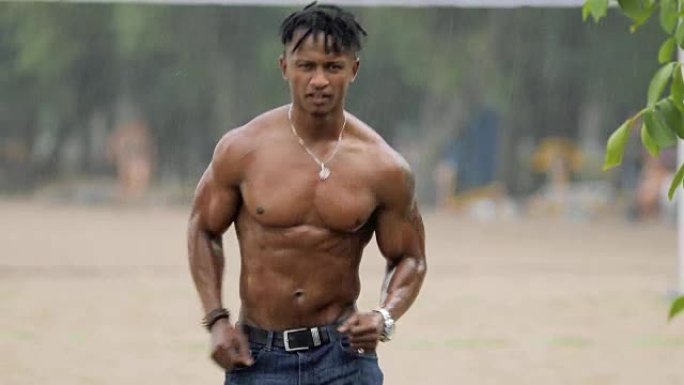 性感的男子气概，肌肉发达的身体在雨天的海滩上奔跑