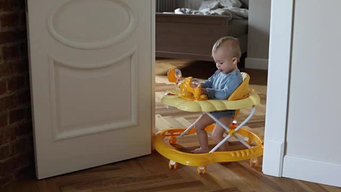 迷人的男婴在婴儿学步车里玩耍