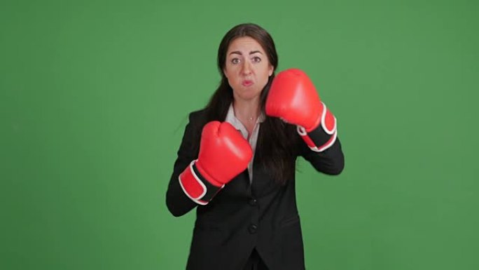 愤怒的女商人穿着绿色背景的拳击手套