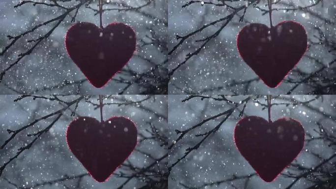 圣瓦伦丁节的冬季抒情场景。红心在背光，挂在无叶的苹果树枝上，在闪闪发光的降雪中，慢动作。
