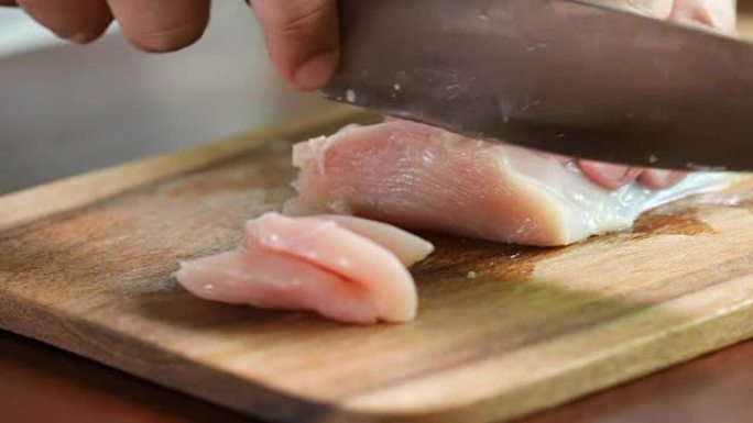 Close up  human hand cutting raw chicken meat on w