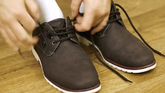 穿白袜子的男人穿鞋系鞋带。系靴子。