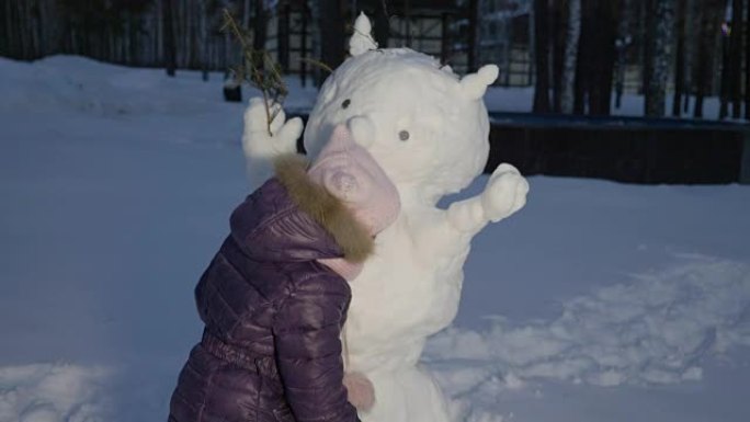 快乐的小女孩拥抱雪人冬天晚上在乡村散步