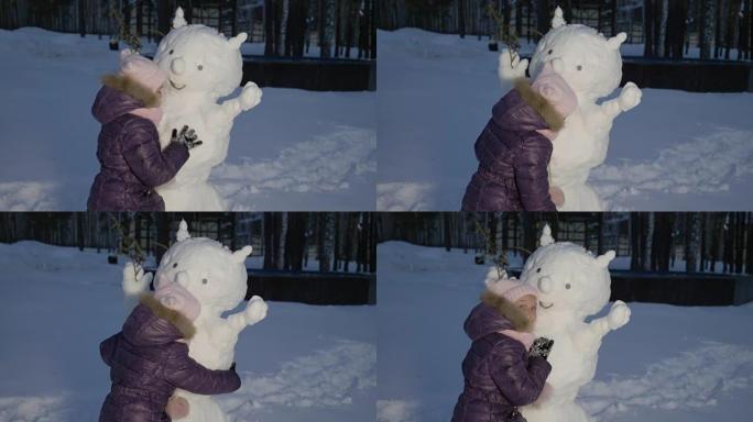 快乐的小女孩拥抱雪人冬天晚上在乡村散步