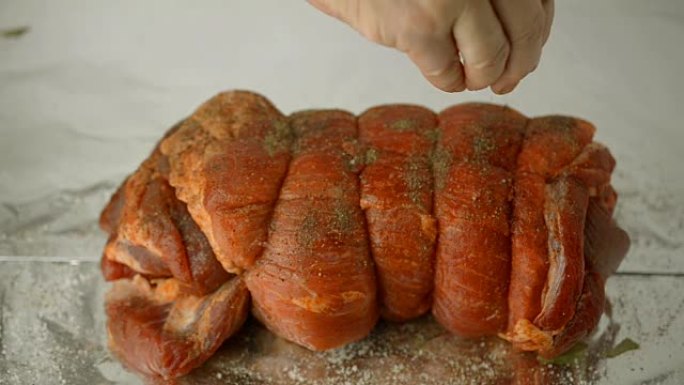 人的手撒上香料和坚果，用猪肉串卷腌制。
