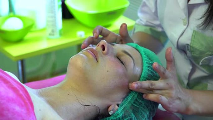 一个年轻女孩在美容师的招待会上。美容师正准备洗脸。面部按摩。