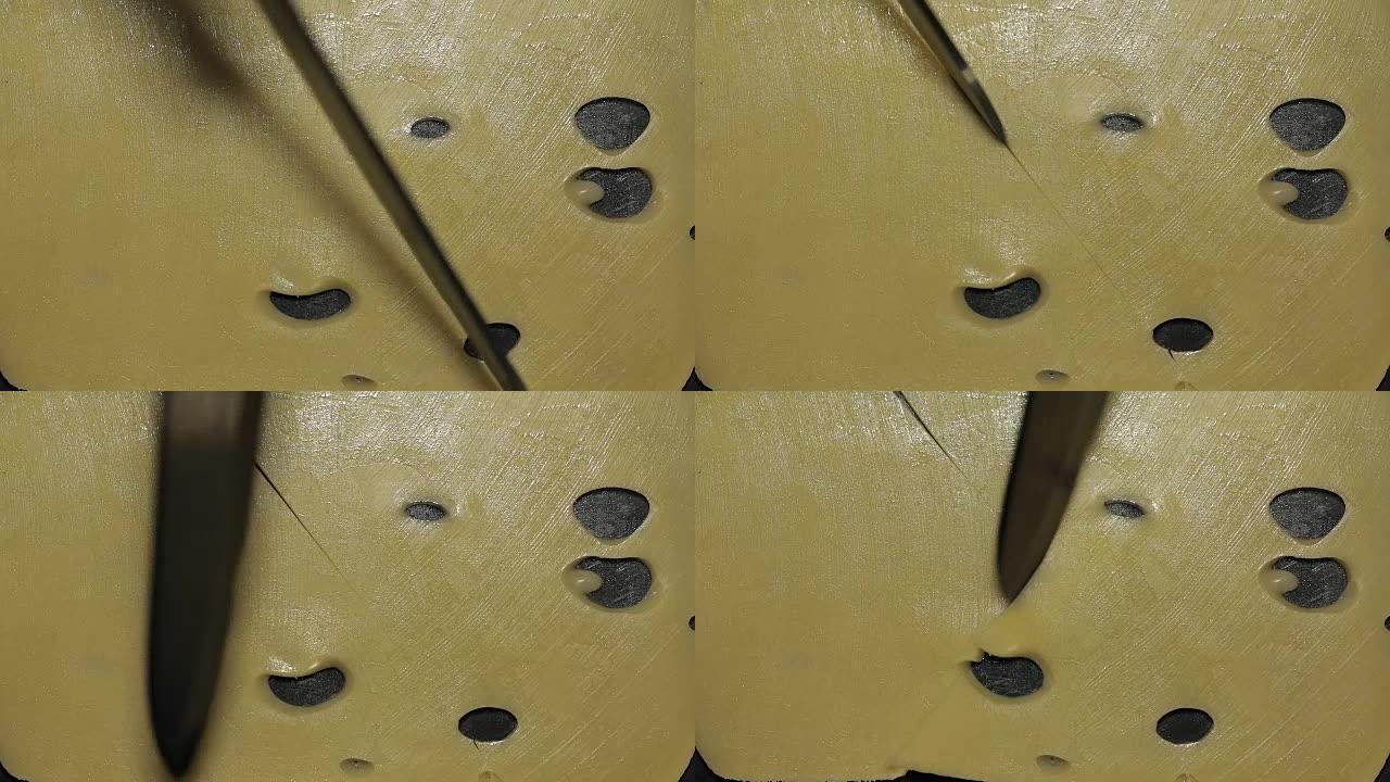 用刀在黑色表面上切割切片的奶酪。特写视图