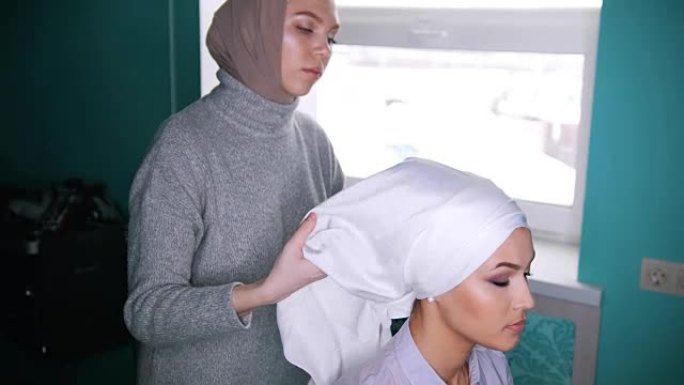 一名穆斯林妇女为漂亮的模特绑头巾
