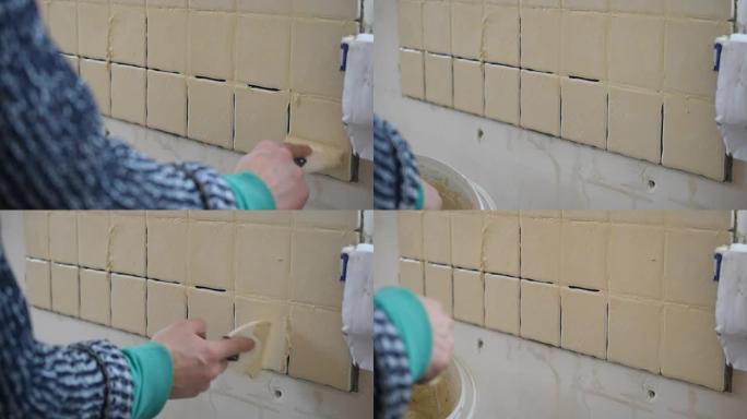 瓷砖工人的手用灌浆填充瓷砖之间的缝隙