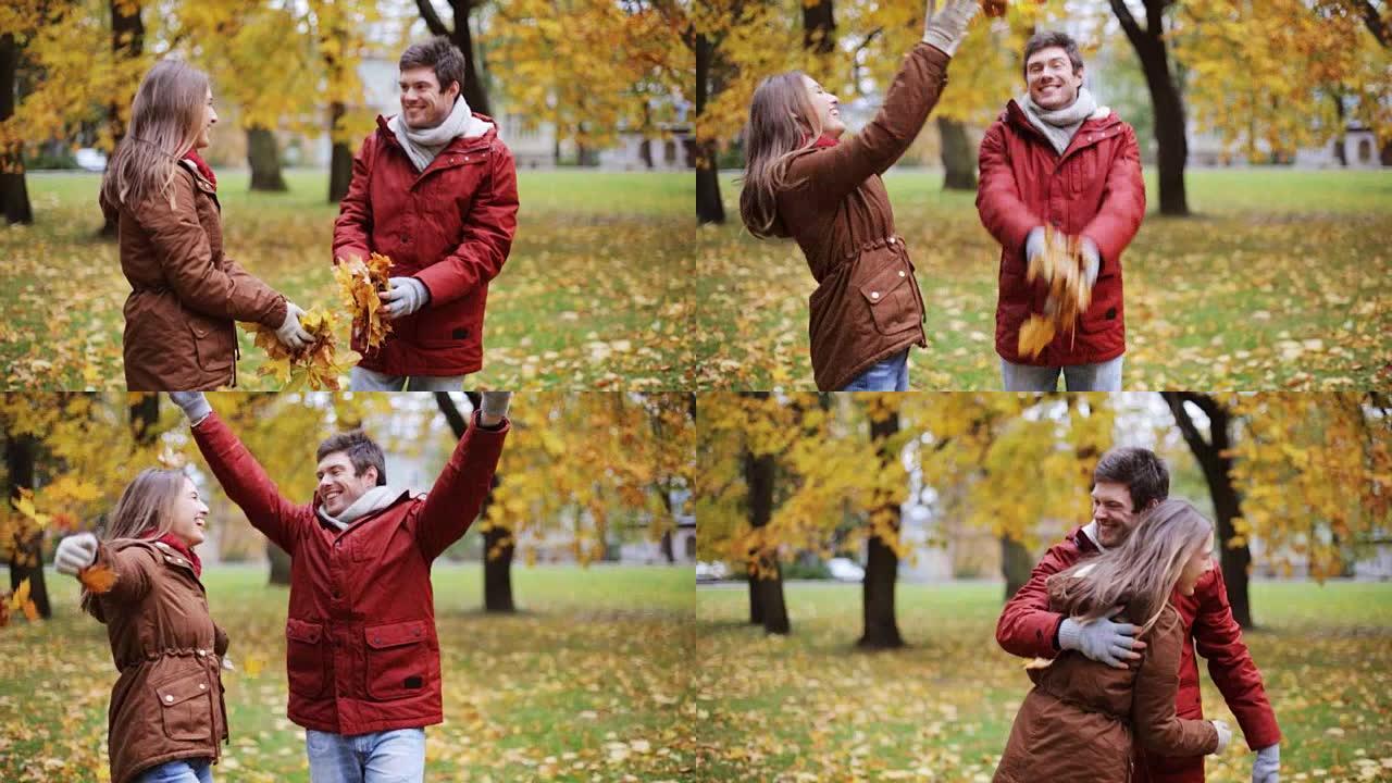 幸福的年轻夫妇在公园里扔秋叶