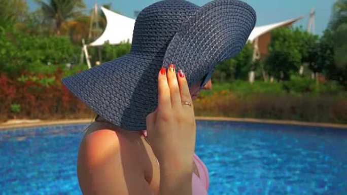 泳池附近戴着蓝色帽子的漂亮女孩。夏日阳光