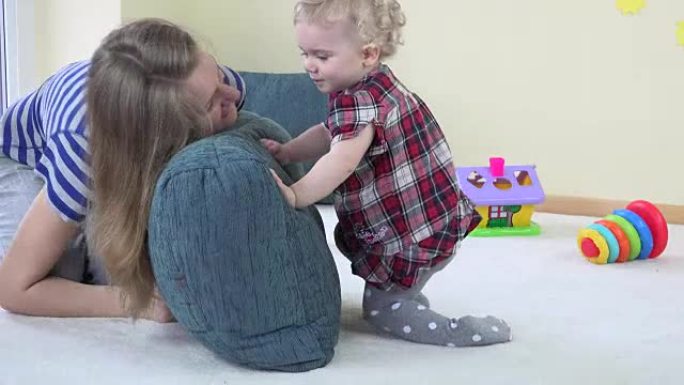 妈妈和蹒跚学步的孩子玩蓝色大枕头，表现出真实的情感