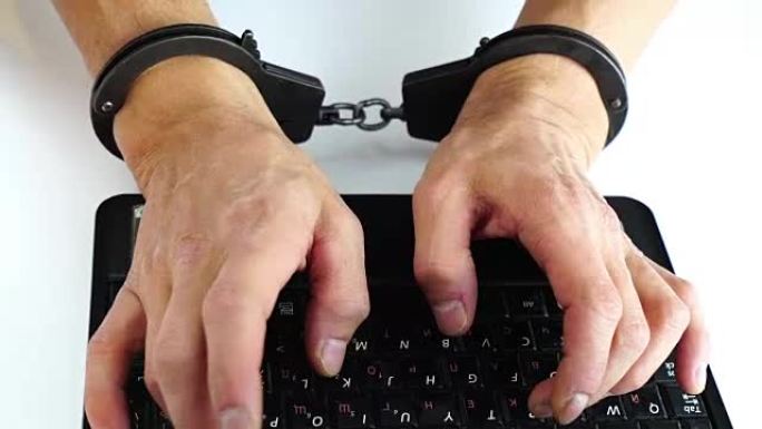 男性手铐在笔记本电脑上打字，犯罪预防，黑客攻击，信息技术，数字犯罪处罚，数据安全，保存软件