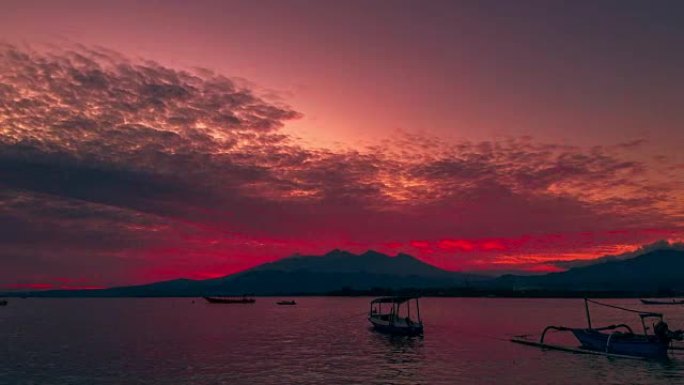 印度尼西亚龙目岛林贾尼火山背景上的吉利岛附近的海洋中的小船延时日出