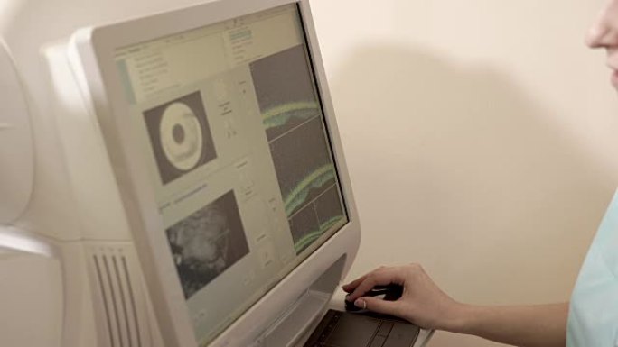 医生坐在视网膜断层扫描设备后面