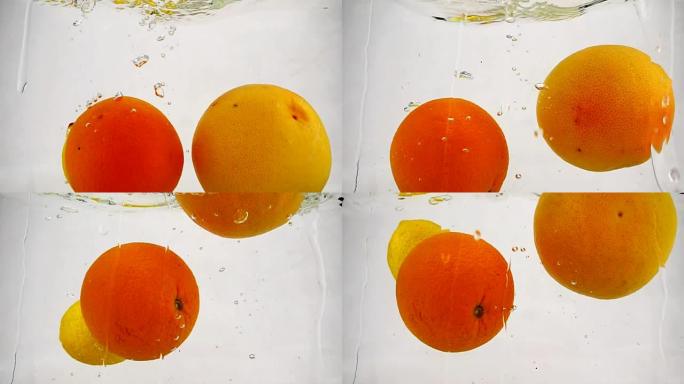 整个葡萄柚，橙子和柠檬随着气泡落入水中。慢动作的柑橘类水果视频。