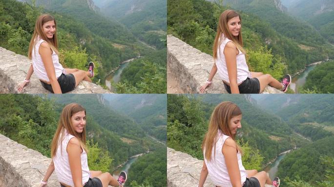 幸福的女人坐下来，欣赏有河的山峡谷景色