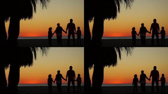家庭周末在棕榈树下的海滩上。火热的日落。父母和两个孩子