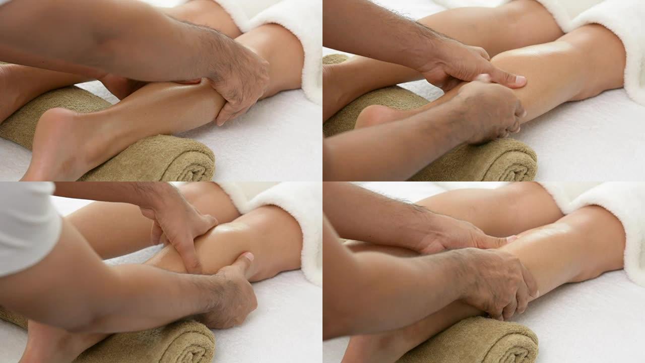 男性治疗师 (按摩师) 在水疗中心为女性提供腿部按摩