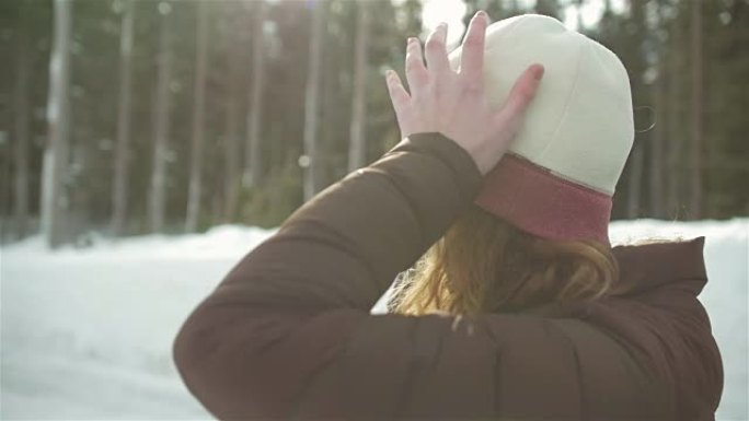 一个美丽的年轻女子在下雪天戴上无檐小便帽的侧写照片