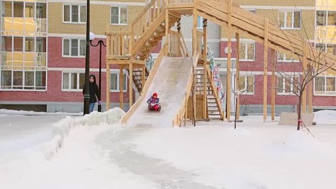 Child and mother riding slides at playground