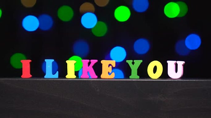 抽象模糊灯光前多色木制字母的彩色单词 “我喜欢你” bokeh背景