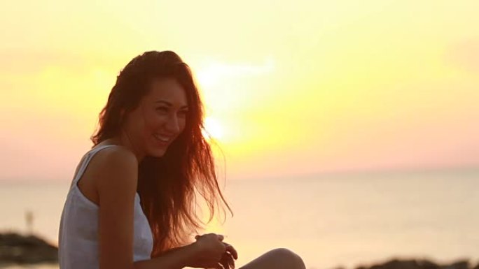 快乐的年轻女子在早晨的海滩上微笑，同时想象着与太阳的玩耍