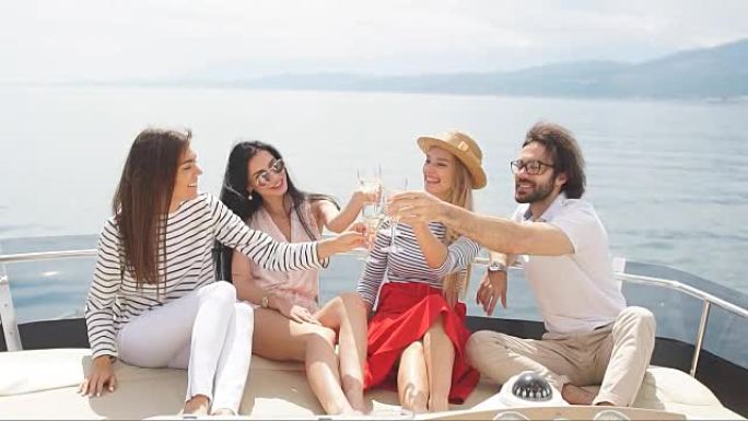 年轻的欧洲游客男孩和女孩在游艇上庆祝他们假期的快乐开始 -- 一群朋友在帆船上敬酒和聚会