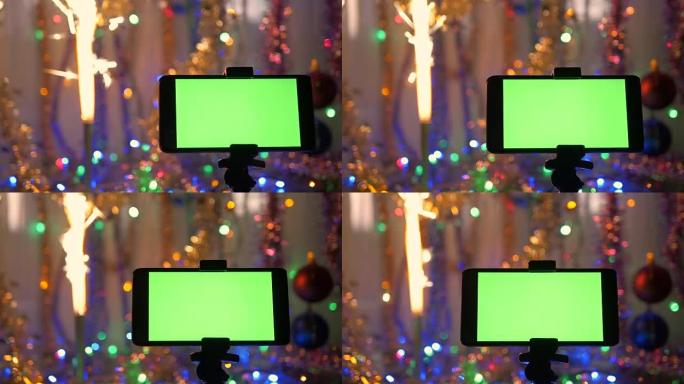 带有绿色屏幕的智能手机，在新年背景上。节日的烟花燃起来了。