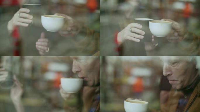 一对年长的情侣通过展示窗喝咖啡的特写镜头