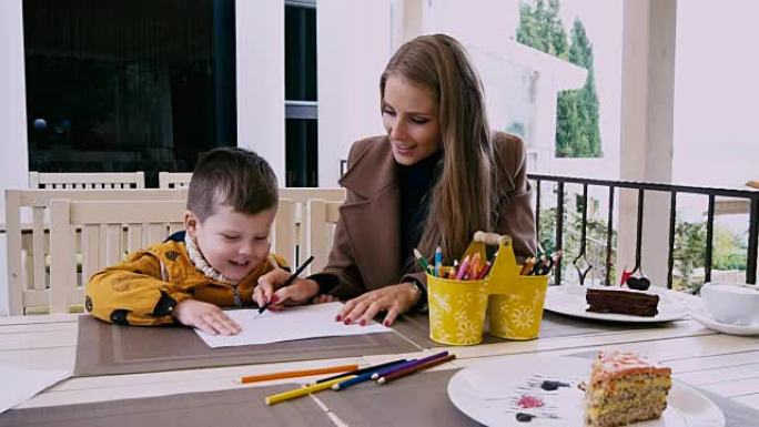 妈妈和小男孩在餐桌上用蜡笔画画