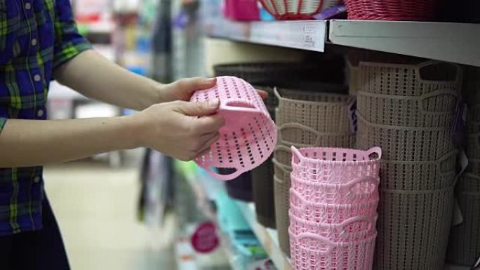 一位年轻女子在超市里选择并购买塑料篮。