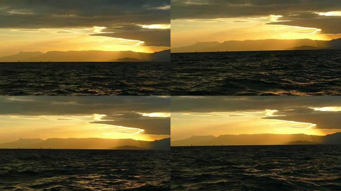 日落时山脉海岸背景上的帆船赛
