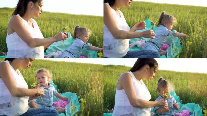 迷人的幸福母女分享爱在毯子上的草地上一起看花