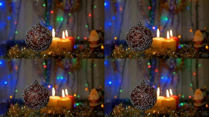 一个美丽的红球在前景旋转。新年和圣诞装饰品。燃烧蜡烛。闪光花环。背景模糊。