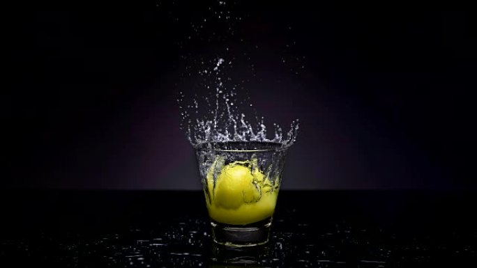 4k Cinemagraph of lemon falling into glass of wate