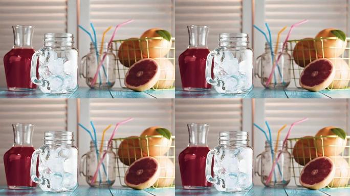 冰块掉进空的梅森罐子里，慢动作。百叶窗对面的质朴蓝色木桌上的新鲜葡萄柚和葡萄柚汁罐。