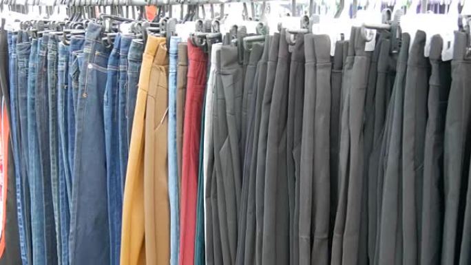 裤子挂在衣架上，女人看衣服选择。跳蚤市场，市场上出售的衣服