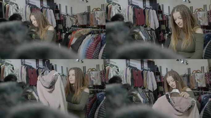 时尚的顾客女孩在商场为她的秋冬季衣柜选择基本的衣服