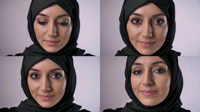 戴着头巾的年轻穆斯林女孩睁开眼睛，看着相机，做梦的概念，灰色背景