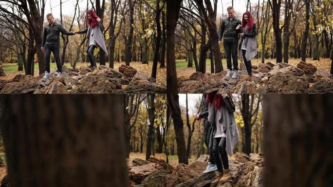 浪漫的年轻夫妇白天牵着手在秋季公园的岩石上散步。有爱心的男朋友握着他女朋友的手。秋天温暖的天气