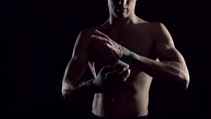 男性拳击手用手包包裹双手。职业拳击手在他手上缠绷带。拳击手在体育馆用拳击包装纸包扎双手