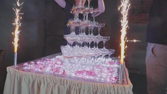 服务员用五彩纸屑和喷泉在金字塔的玻璃杯中倒香槟