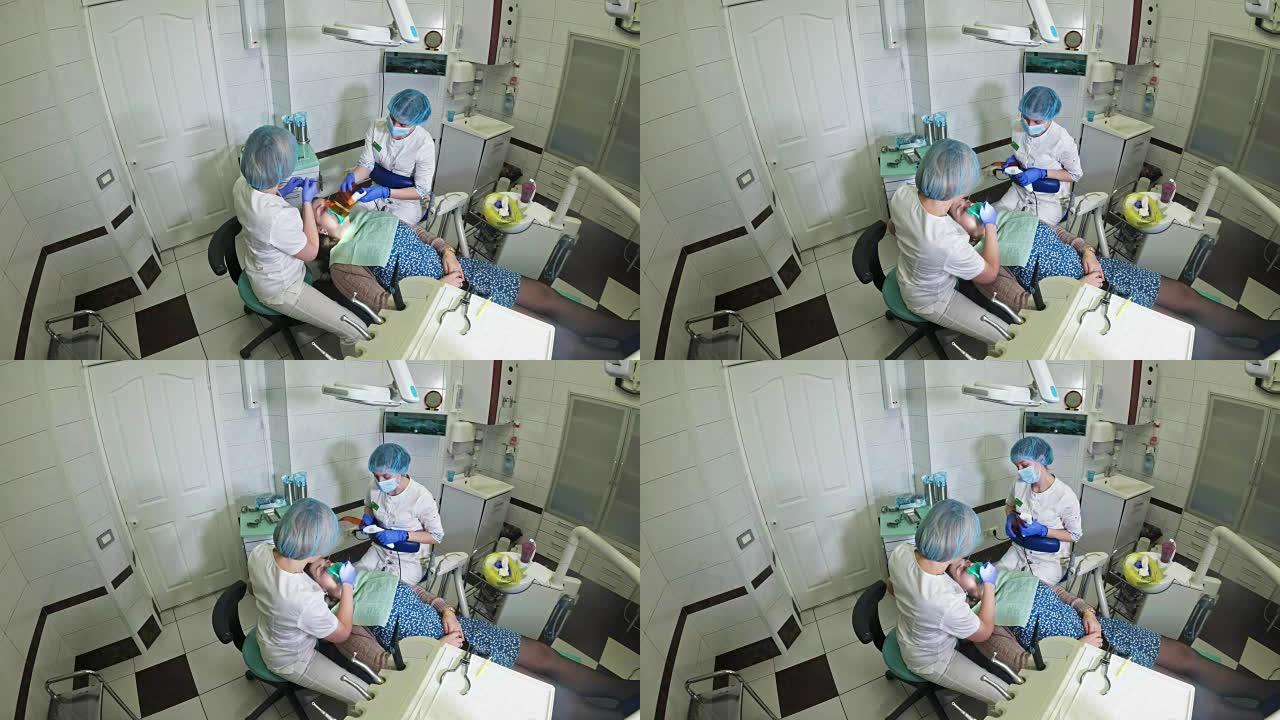 牙医诊所的女人接受牙科治疗以填补牙齿上的空洞。牙科修复和复合材料用紫外光和激光聚合。